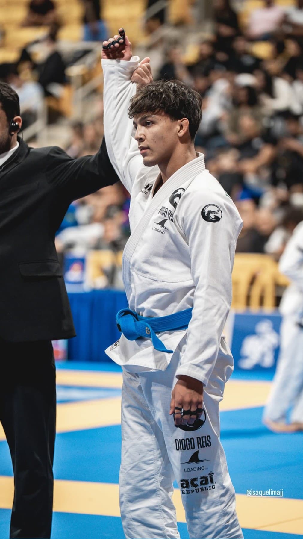 Isaque de kimono com o braço erguido no campeonato