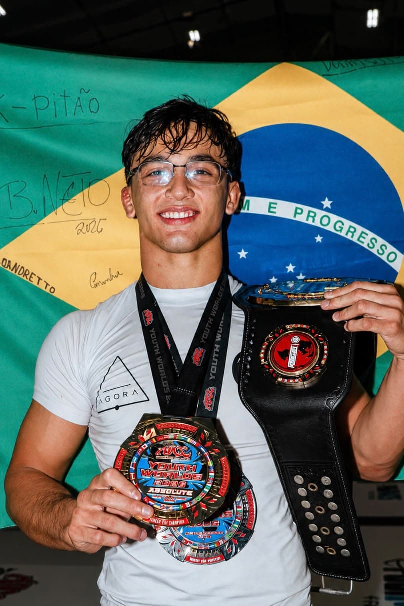 Isaque com medalha e cinturão diante da bandeira do Brasil