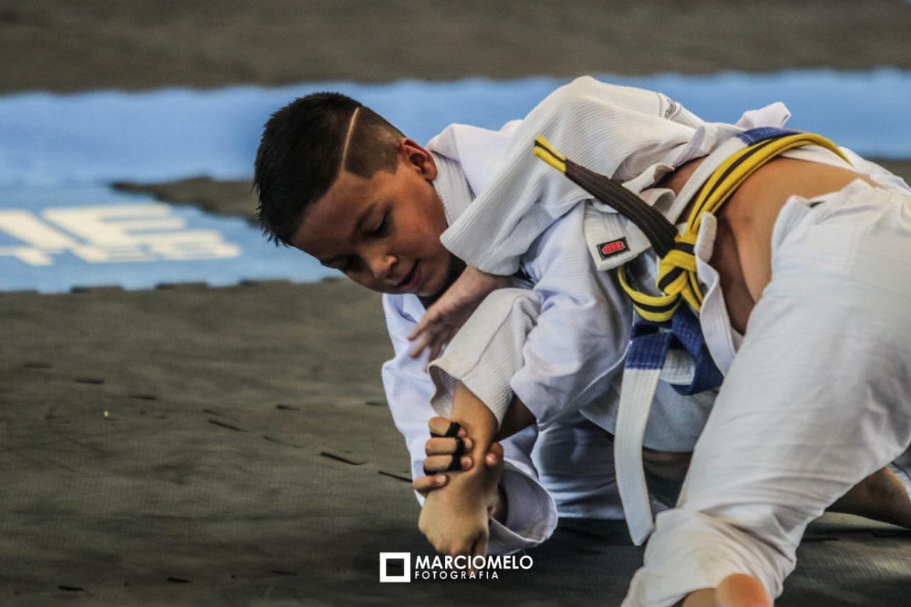Isaque disputando uma luta de jiu-jitsu no tatame