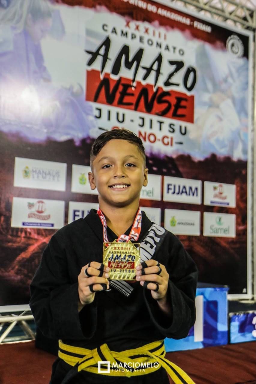 Isaque de kimono exibindo suas medalhas